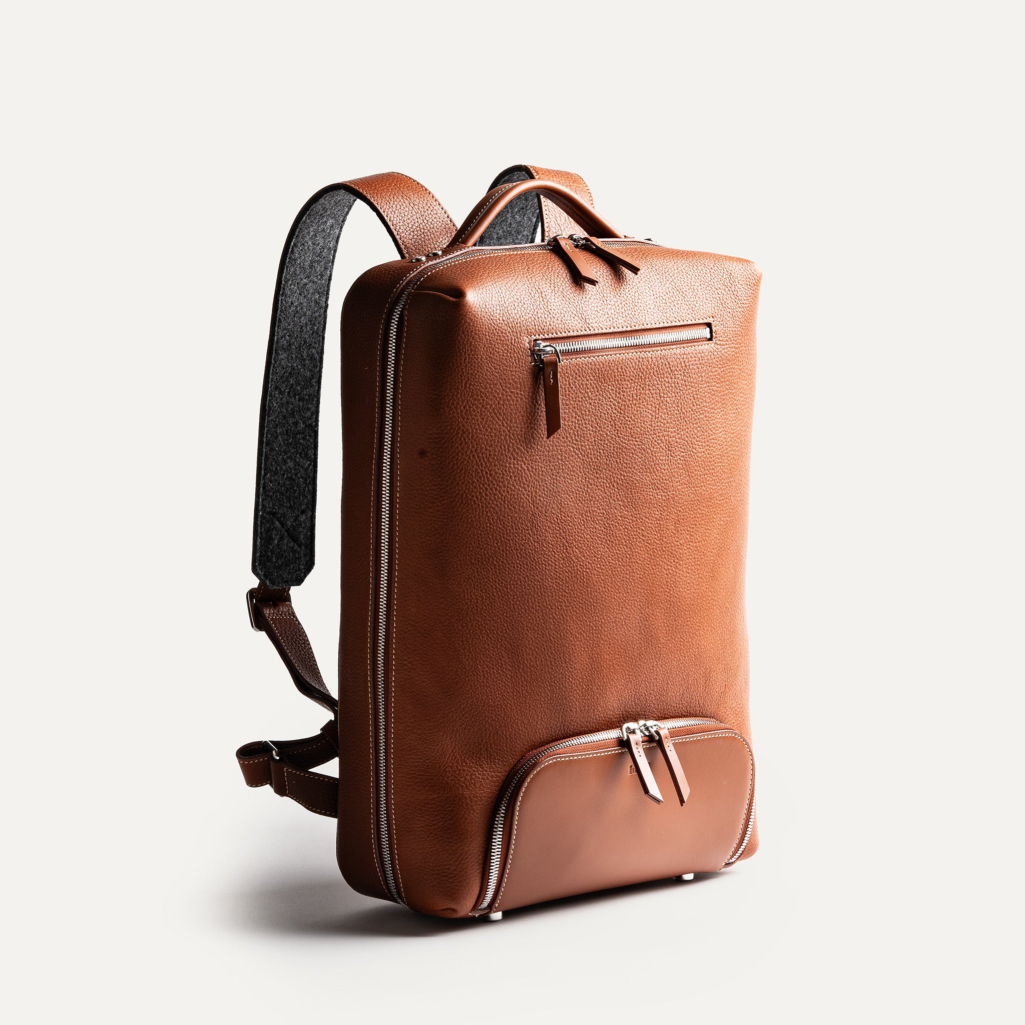 Sac à dos homme élégant en cuir cognac avec poches zippées et design minimaliste.