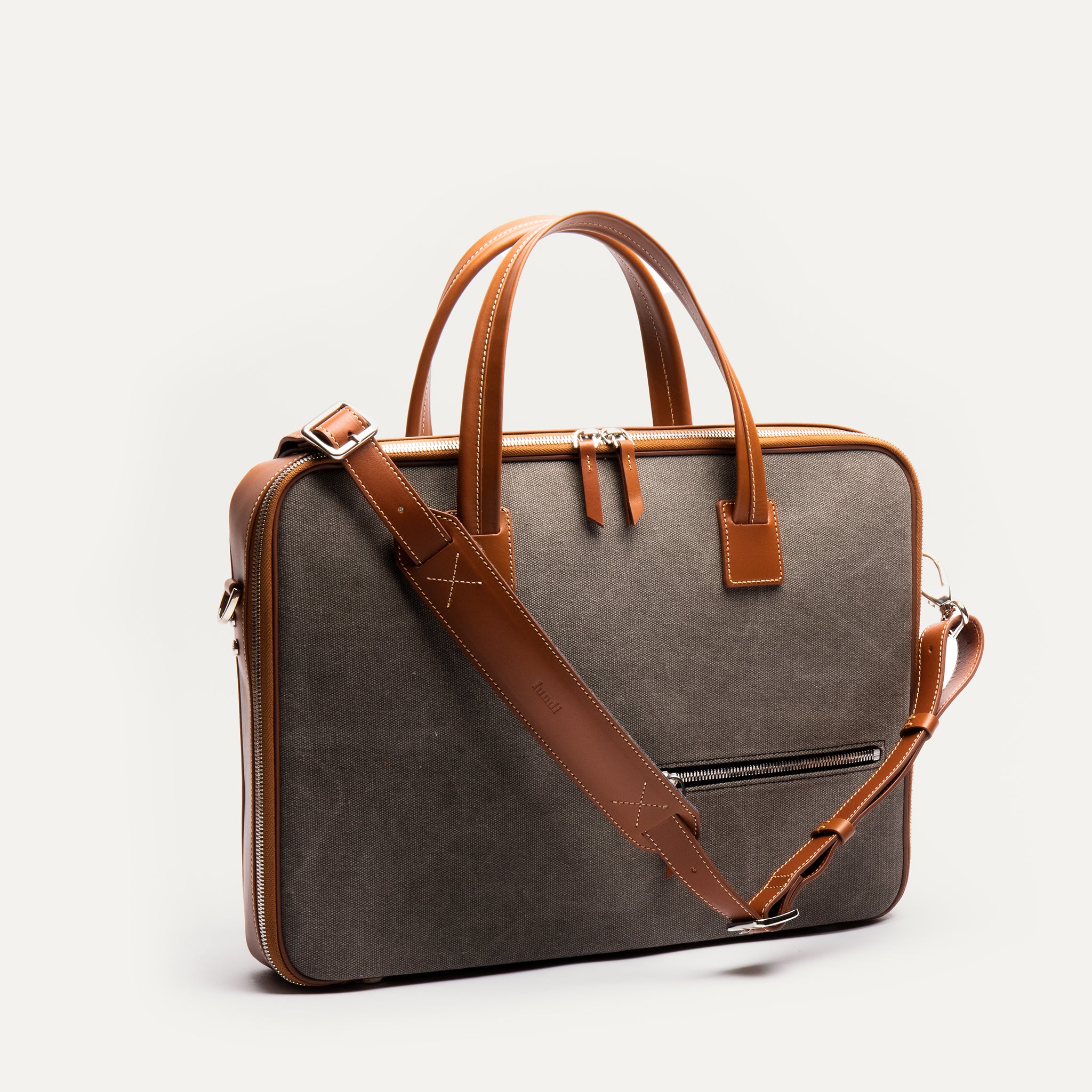 Sac à bandoulière homme en cuir et toile cognac, fonctionnel et élégant pour transporter tout le nécessaire.