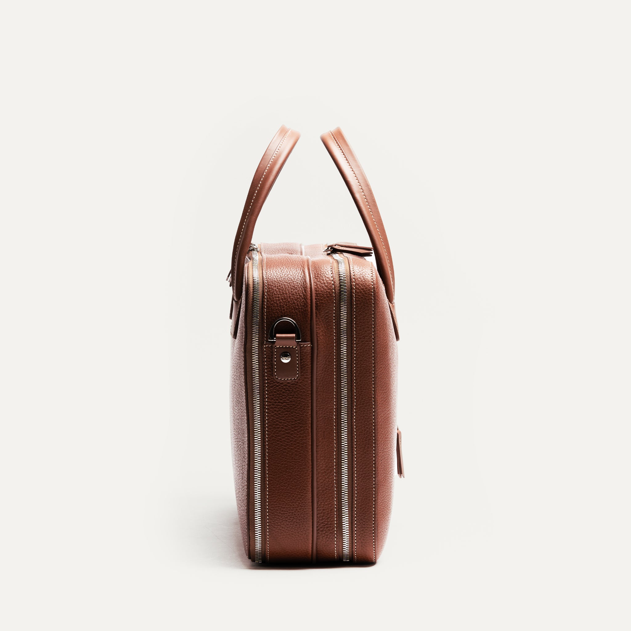 ce sac pour ordi portable en cuir cognac comporte des fermetures éclairs YKK de la gamme Excella à double curseur.